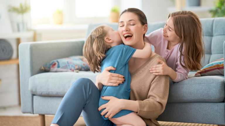 Mom hugging her child while kissing her.