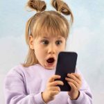 A child with a shocked expression while looking at a gadget screen.