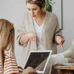 A mom lecturing her child about gadget use while resting her feet on a table with food.