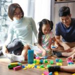 A family sitting together, happily playing with building blocks.