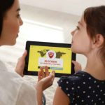 A mom guiding her daughter on a tablet, helping her block unwanted apps that are inappropriate for her age.