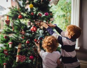 Children putting ornaments in the Christmas tree.